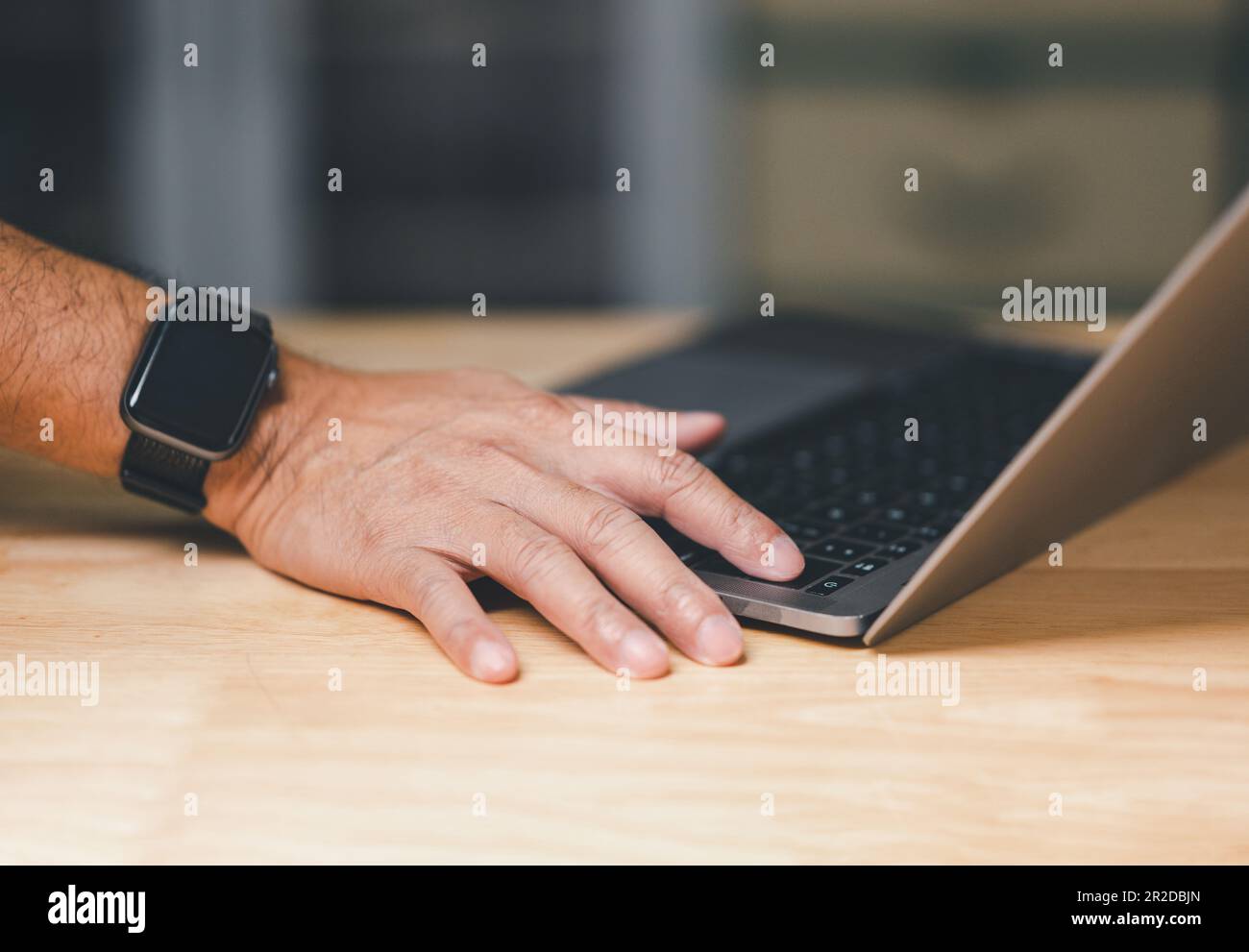 Man uses his finger to press button to turn off, closed, shut down laptop computer on desk, before going home for saving energy, save global environme Stock Photo