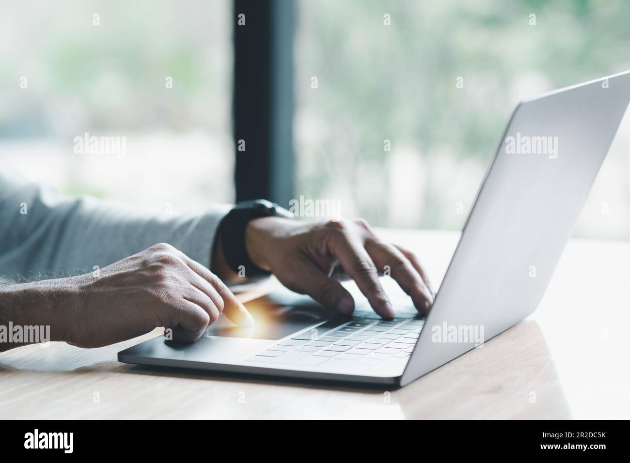 Man uses his finger to press button to turn off, closed, shut down laptop computer placed on desk, is time to finish each day before going home for sa Stock Photo