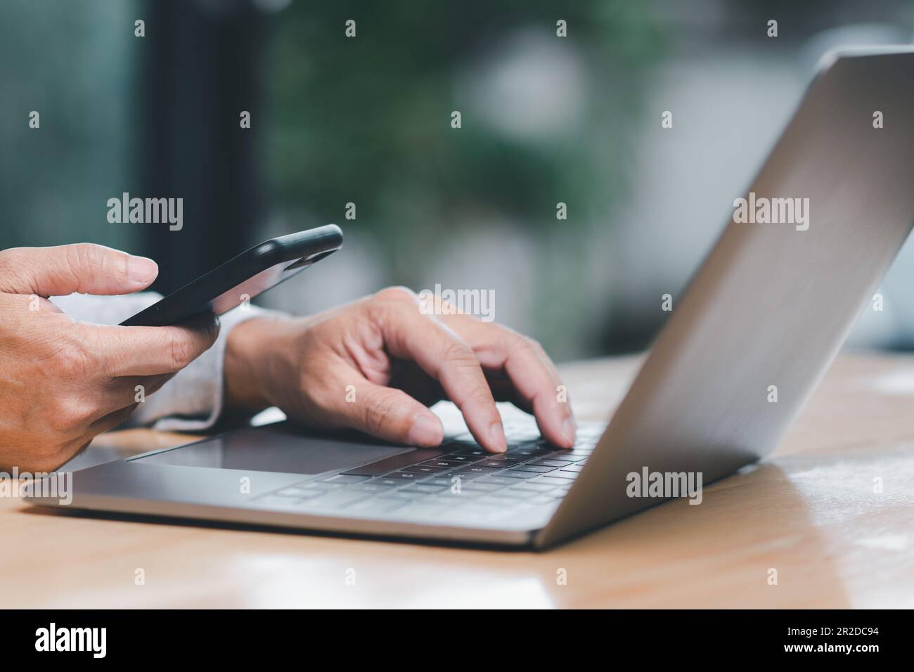 Man uses his finger to press button to turn off, closed, shut down laptop computer placed on desk, is time to finish each day before going home for sa Stock Photo