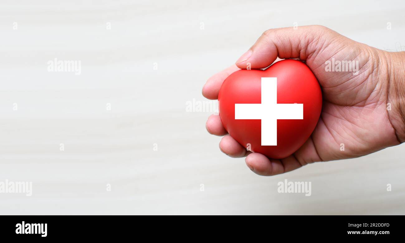 A red cross is a symbol of medical health. Hand holding a heart and on ...