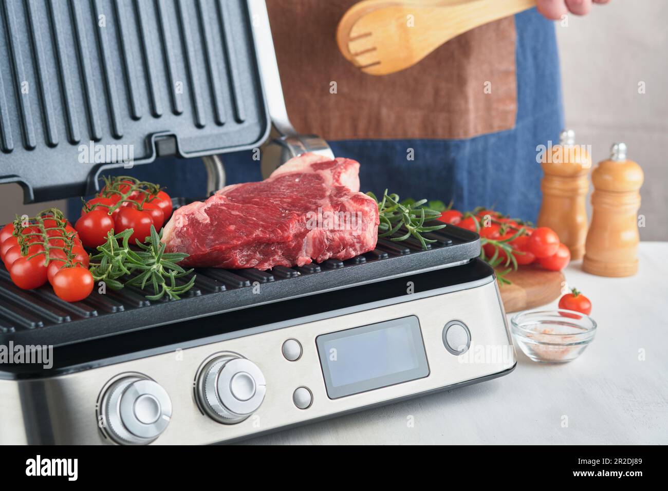 Raw prime steaks on electric grill. Chef male hand holding steak Ribeye
