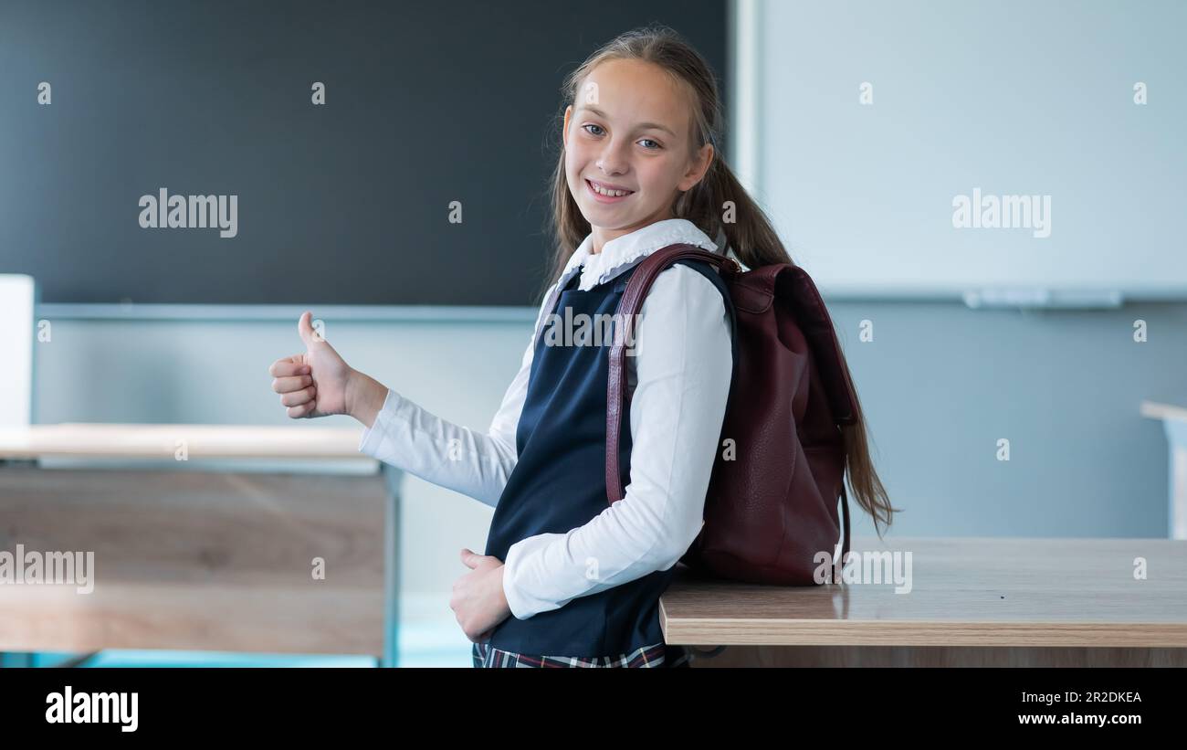 Portrait of a caucasian schoolgirl with a backpack in the classroom ...