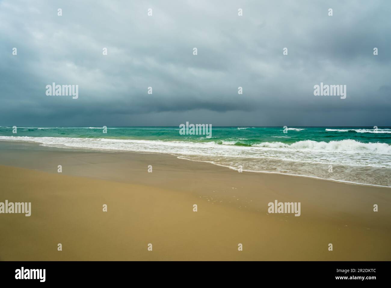 Rain clouds over the ocean, with surf waves breaking on a sandy beach. Flinders Beach, North Stradbroke Island, Queensland, Australia Stock Photo