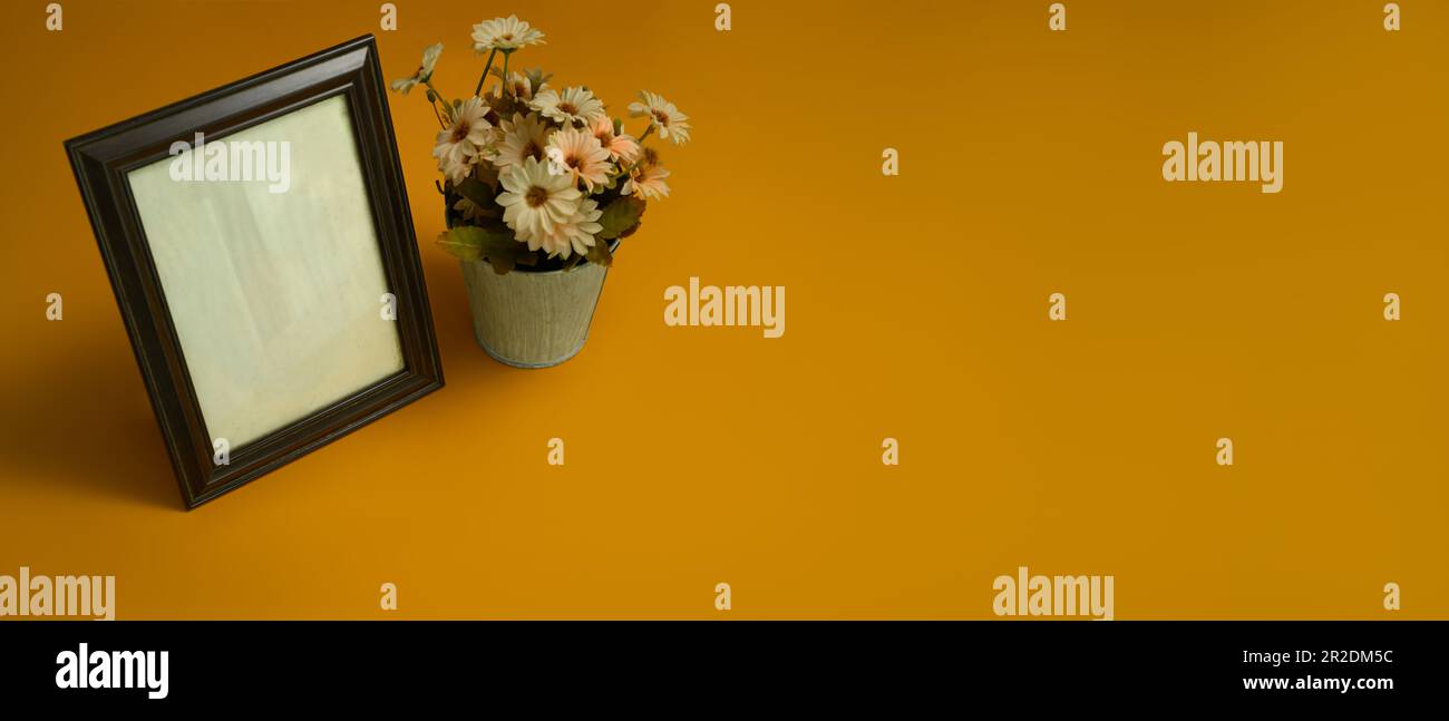 Blank wooden photo frame with flower pot on yellow background. Empty ...