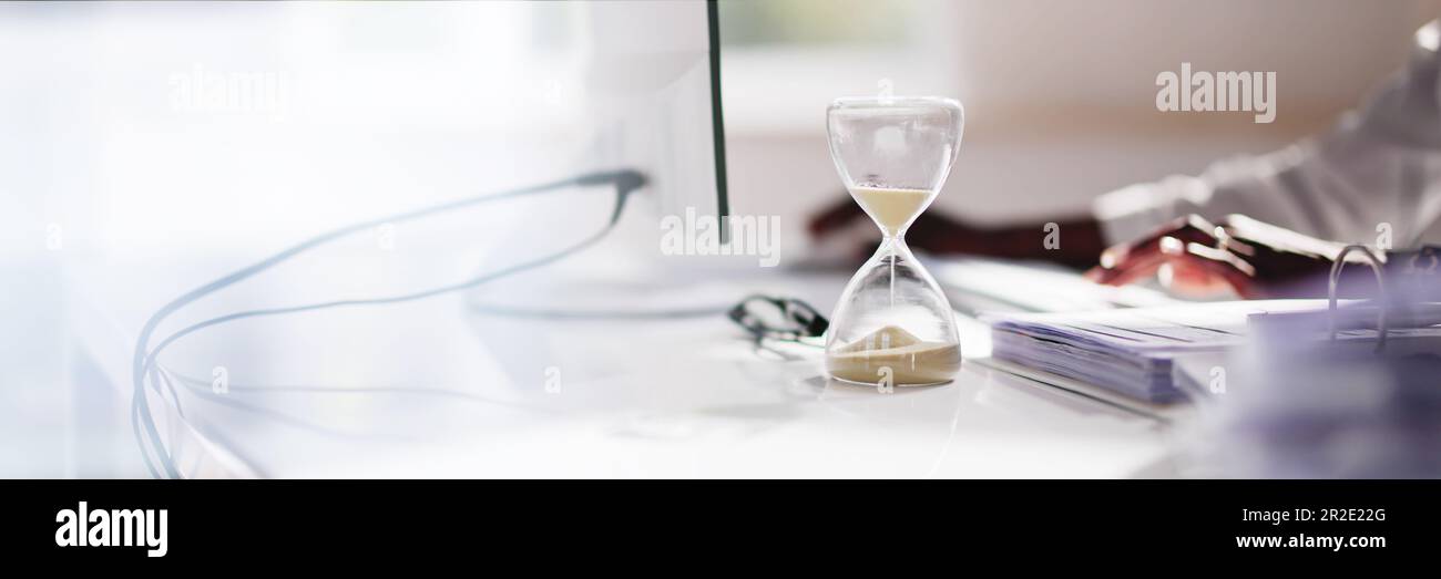 Late Invoice And Billing Deadline With Hourglass At Desk Stock Photo