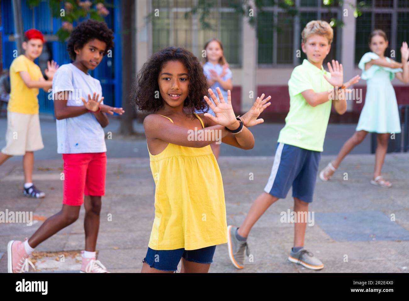 Smiling african american preteen girl dancing with tweenagers on city ...