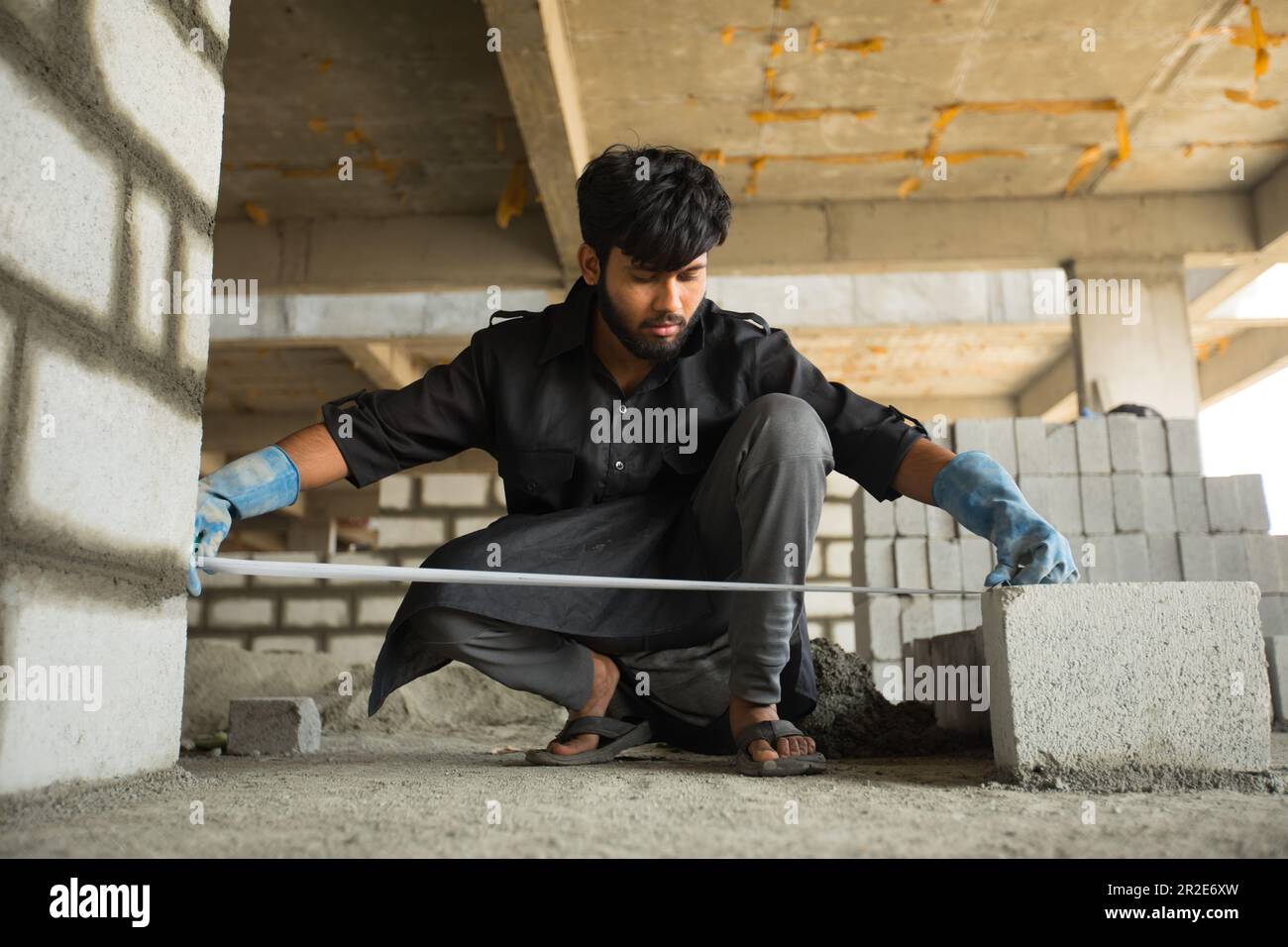 construction worker levels or measures a cement brick wall using measuring tape Stock Photo