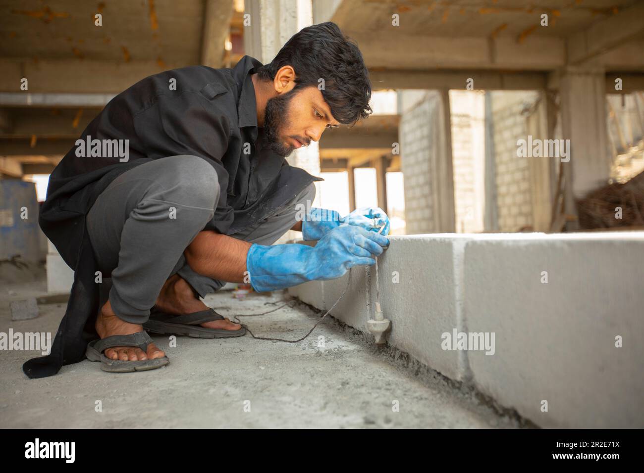 A construction worker uses a plumb bob measuring tool to accurate a