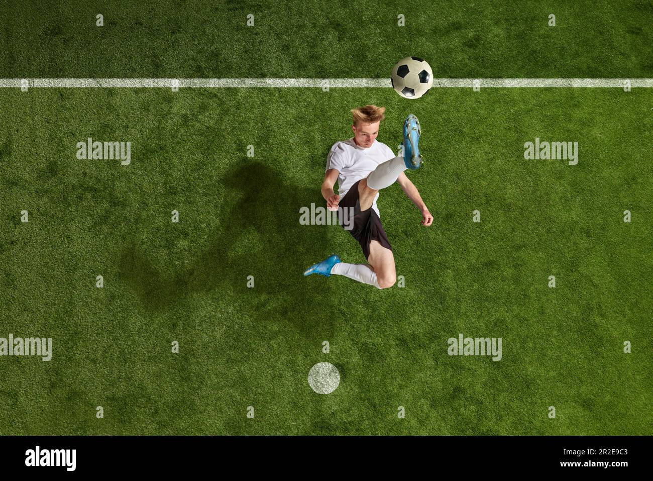 One soccer football player jumping and kicking the ball over field