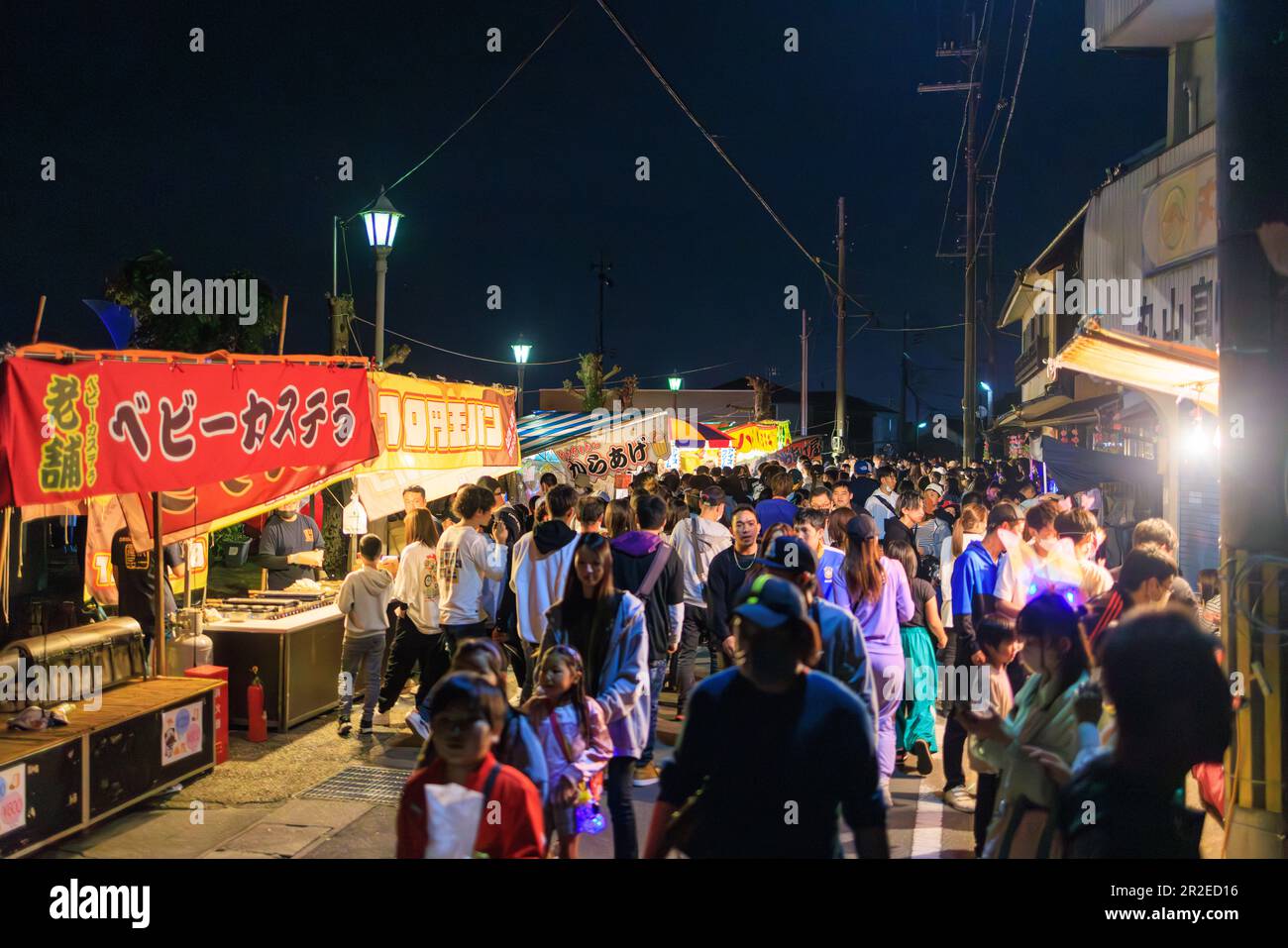 Kato, Japan - May 3, 2023: Crowd walks by bright food stall lights at outdoor festival Stock Photo