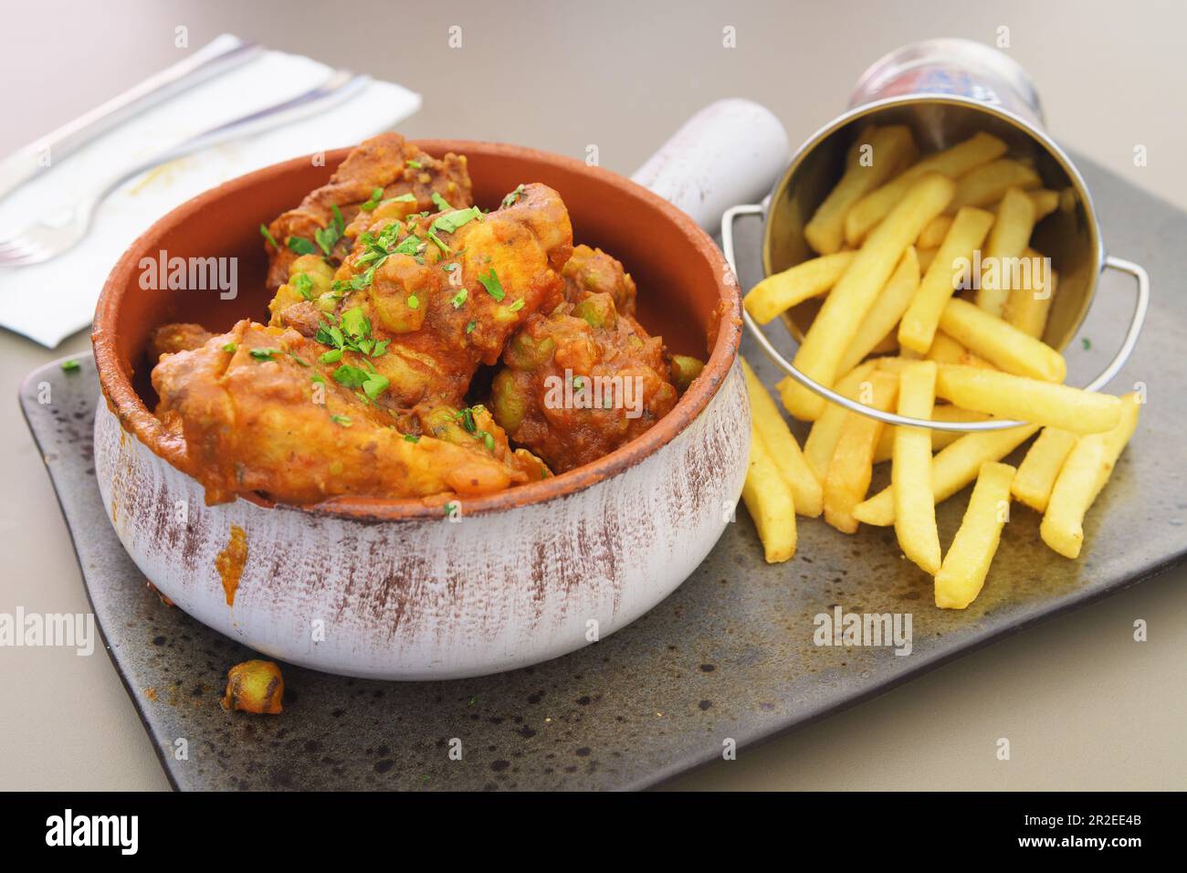 Tasty spicy rabbit stew in tomato sauce with French fries as a side dish in a nicely plated arrangement. Traditional food, gourmet and culinary concep Stock Photo