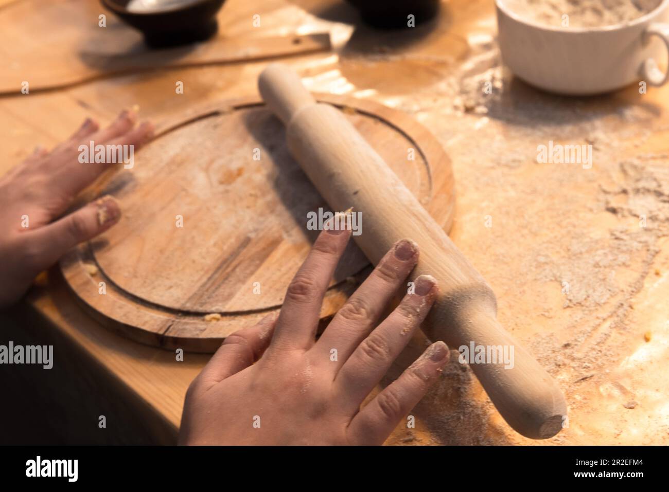 Chef hands and a wooden rolling pin, bakery equipment close up photo with selective soft focus Stock Photo