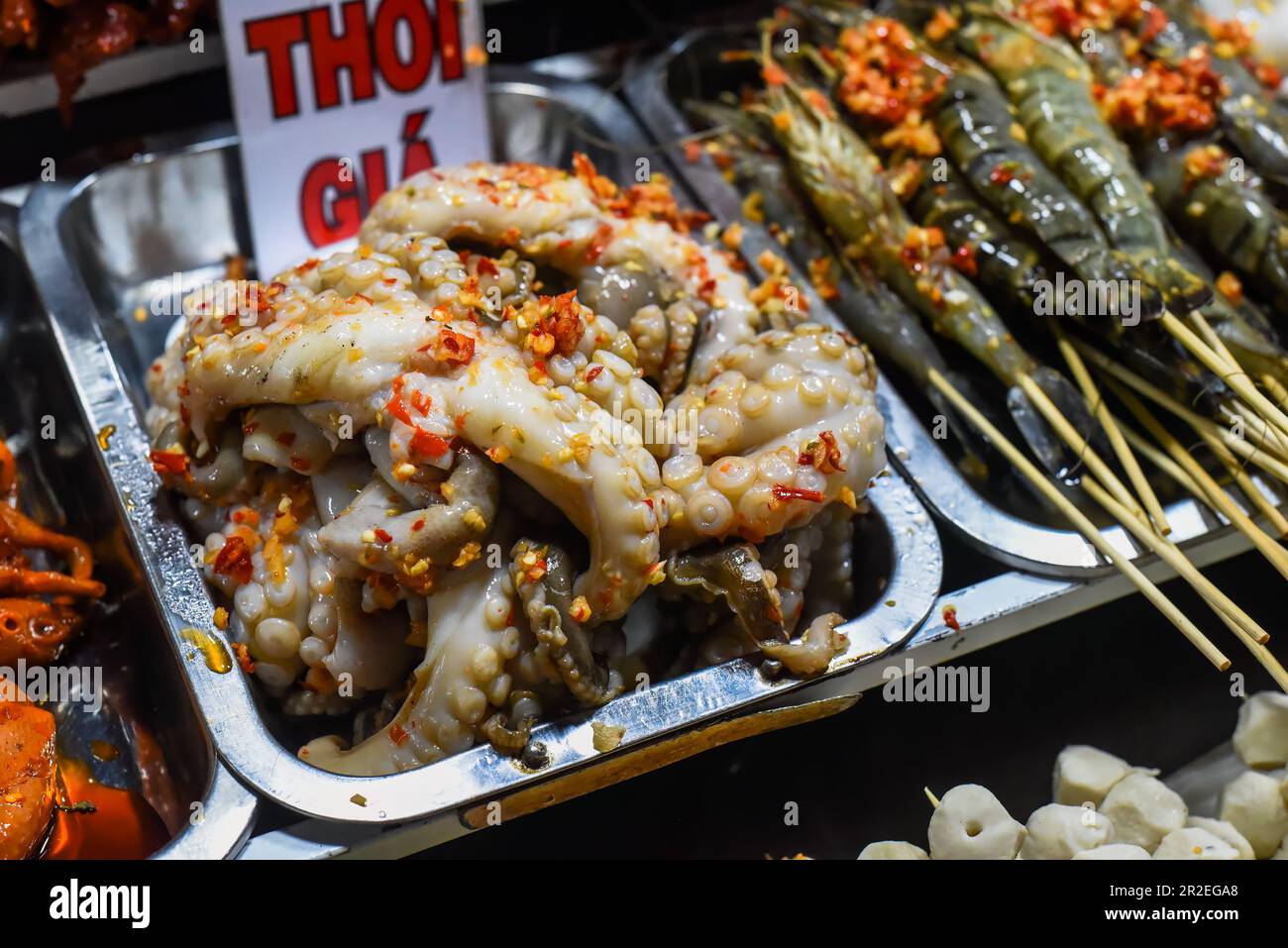 Many snacks and seafood in vietnamese night market with signs with vietnamese text 'time, price' translation Stock Photo