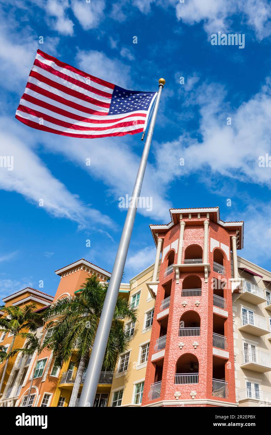 The American national flag flies in front of a colorful house facade ...
