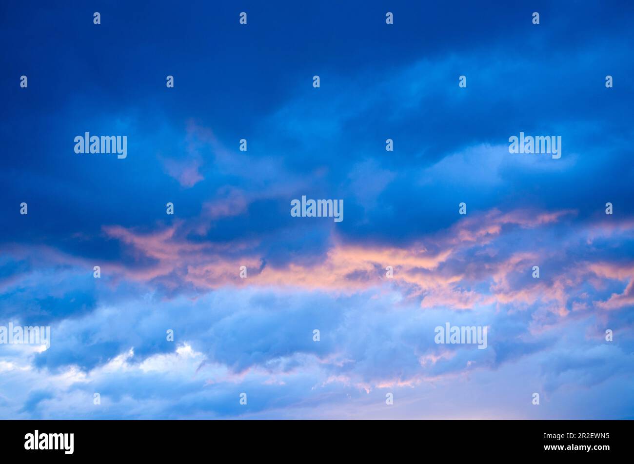 Beautiful dark blue clouds with pink and orange colours.  Colourful skies at sunrise or sunset. Stock Photo