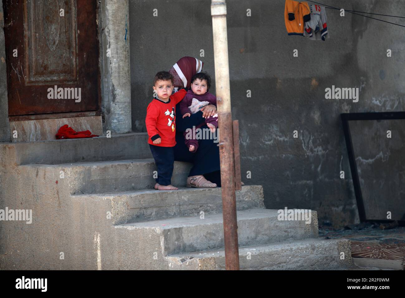 A mother and young children are seen in front of a destroyed building belonging to the Al-Bashir Family after the Israeli attacks in Deir Balah, Gaza City. Palestine. Stock Photo