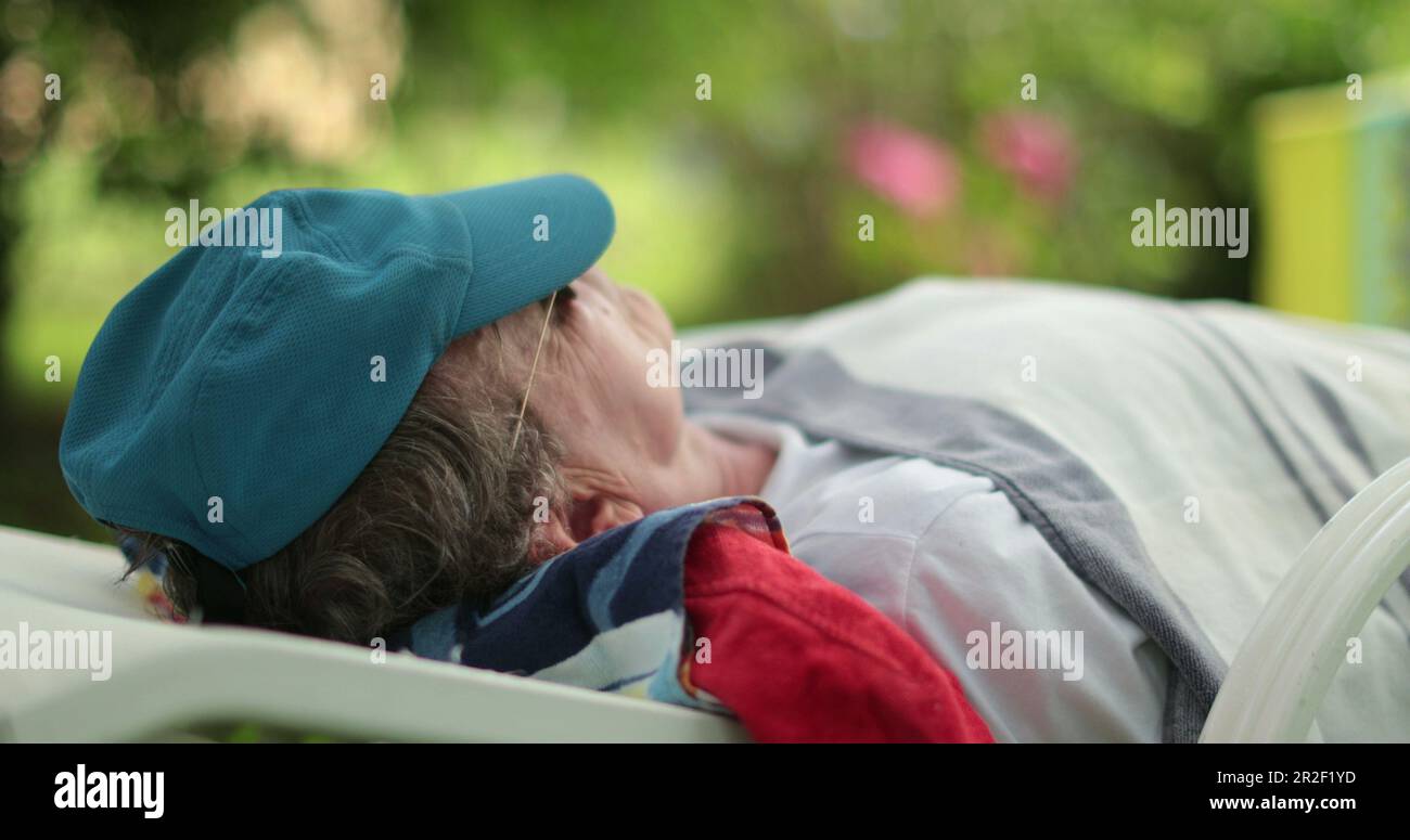 Man sleeping lying down outside. Older retired person napping outdoors