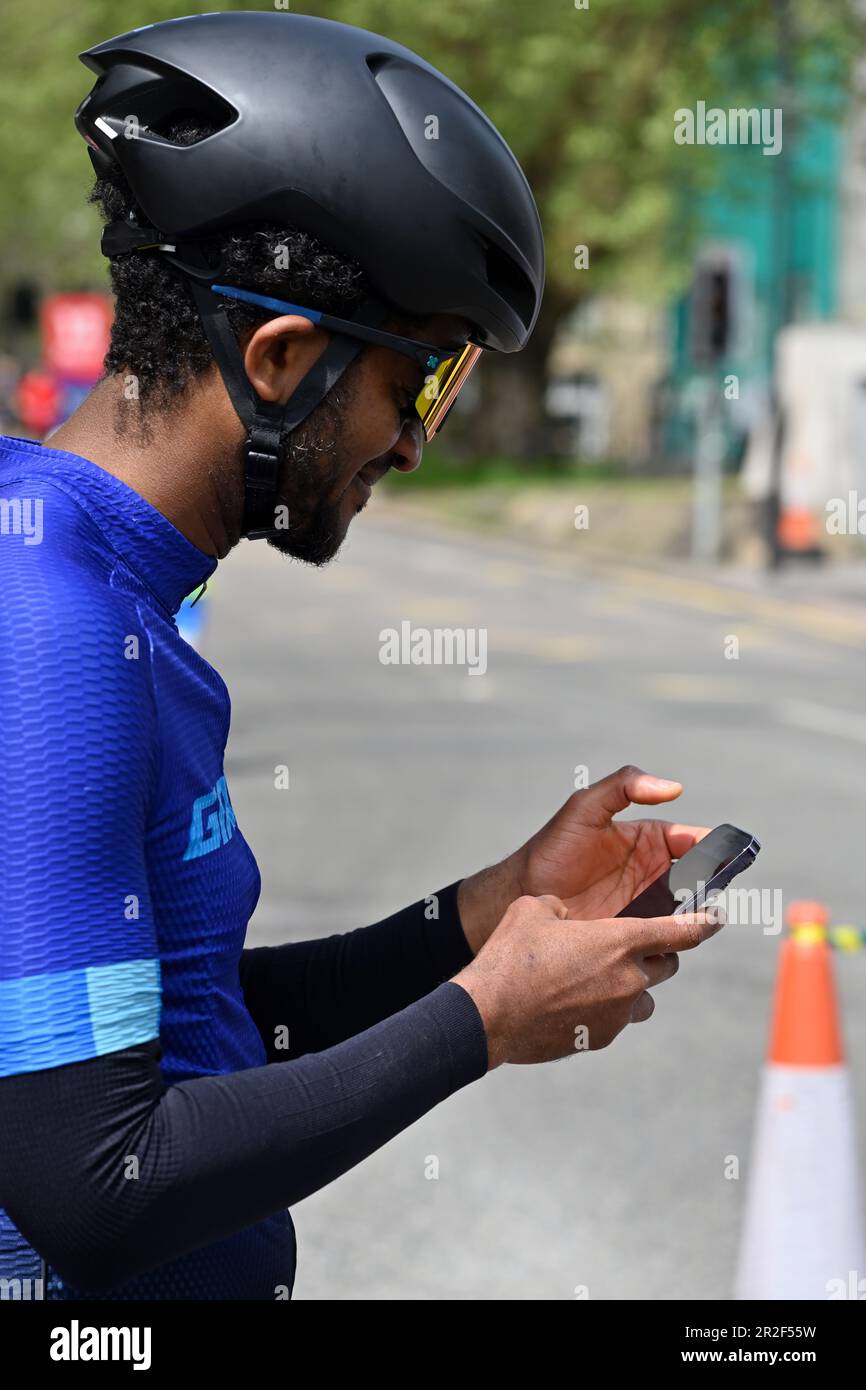 Male cyclist with sunglasses and helmet looking at mobile phone when stopped off the bike Stock Photo