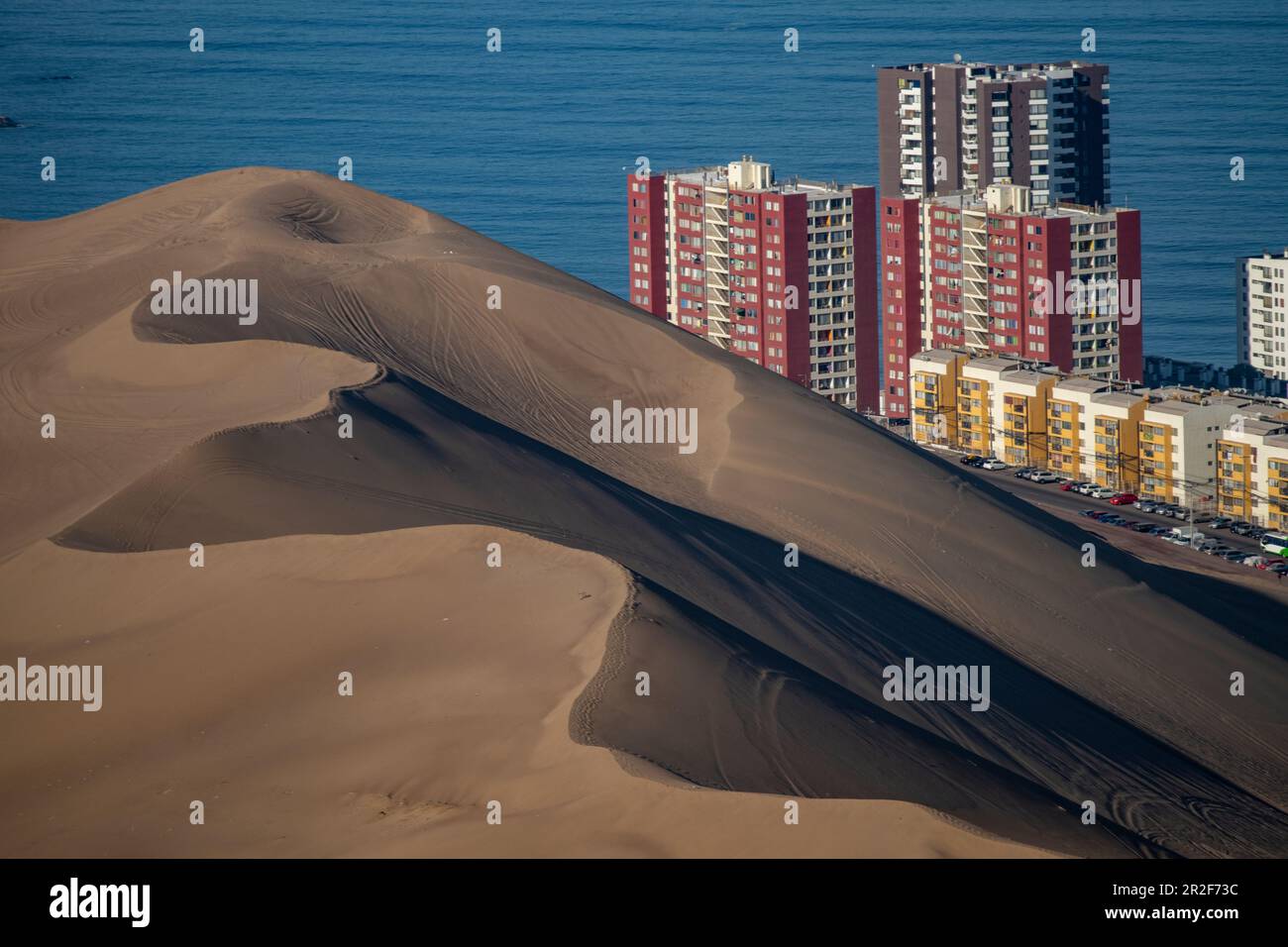 A massive sand dune and skyscrapers on the coast, seen from the inland road, near Iquique, Tarapaca, Chile, South America Stock Photo