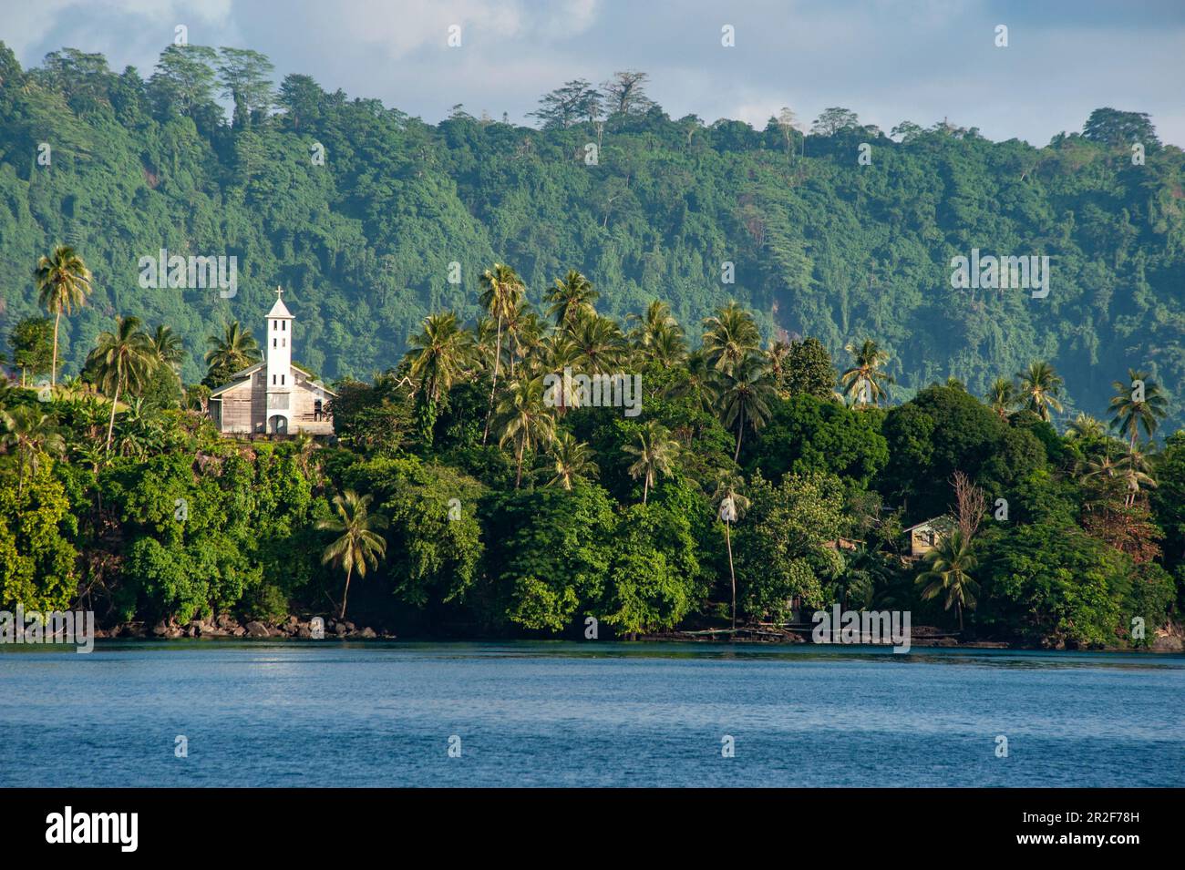 A lonely church stands on a crest surrounded by lush vegetation over the water, Garove Island, Vitu Islands, West New Britain Province, Papua New Guin Stock Photo