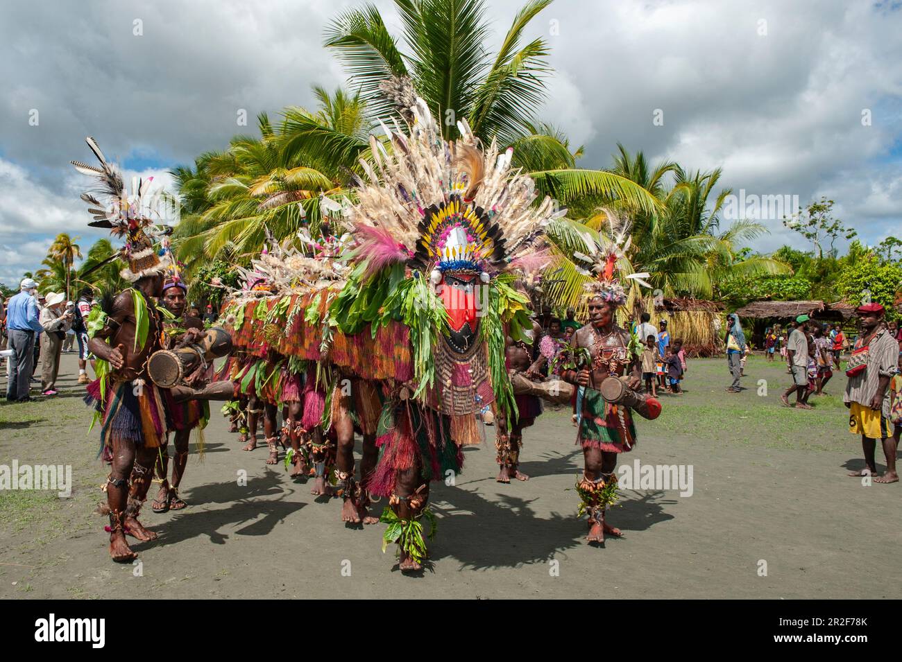 Men in colorful costumes perform a folklore dance to greet passengers on an expedition cruise ship, Kopar, East Sepik Province, Papua New Guinea, Sout Stock Photo