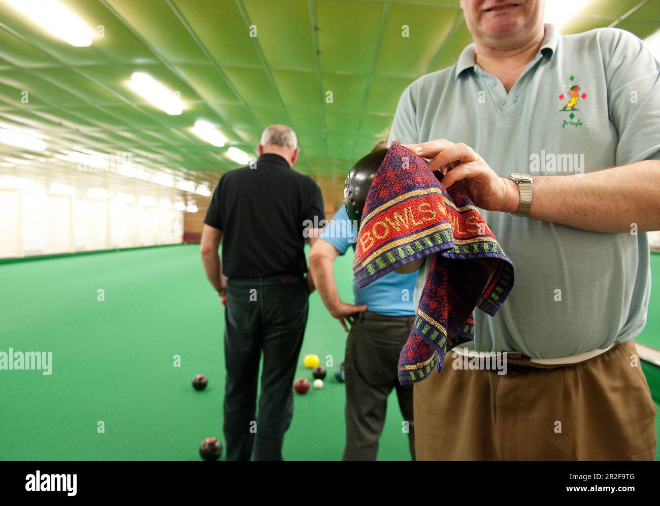 A man cleans his bowl at the Ayr Indoor lawn bowling Green in Scotland Stock Photo
