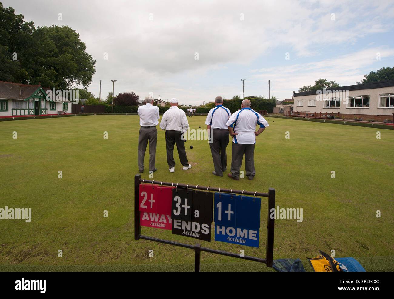 Men play bowls in front of the score cards at the Mauchline lawn bowling green in Mauchline; Ayrshire, Scotland, UK Stock Photo
