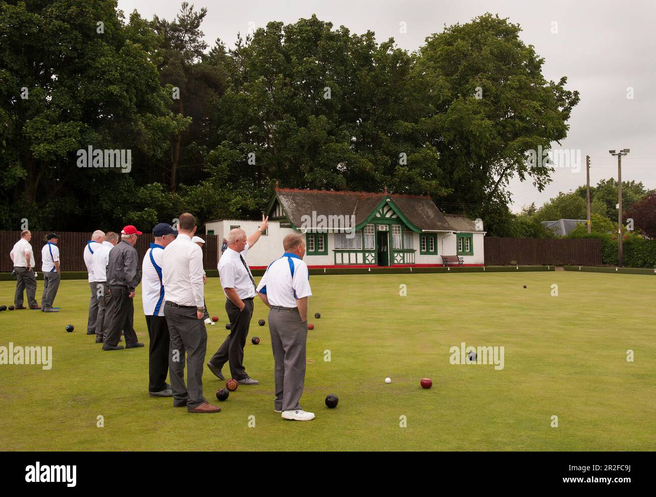 A large crowd of men play bowls in front of the pavilion at the Mauchline lawn bowling green in Mauchline; Ayrshire, Scotland, UK Stock Photo