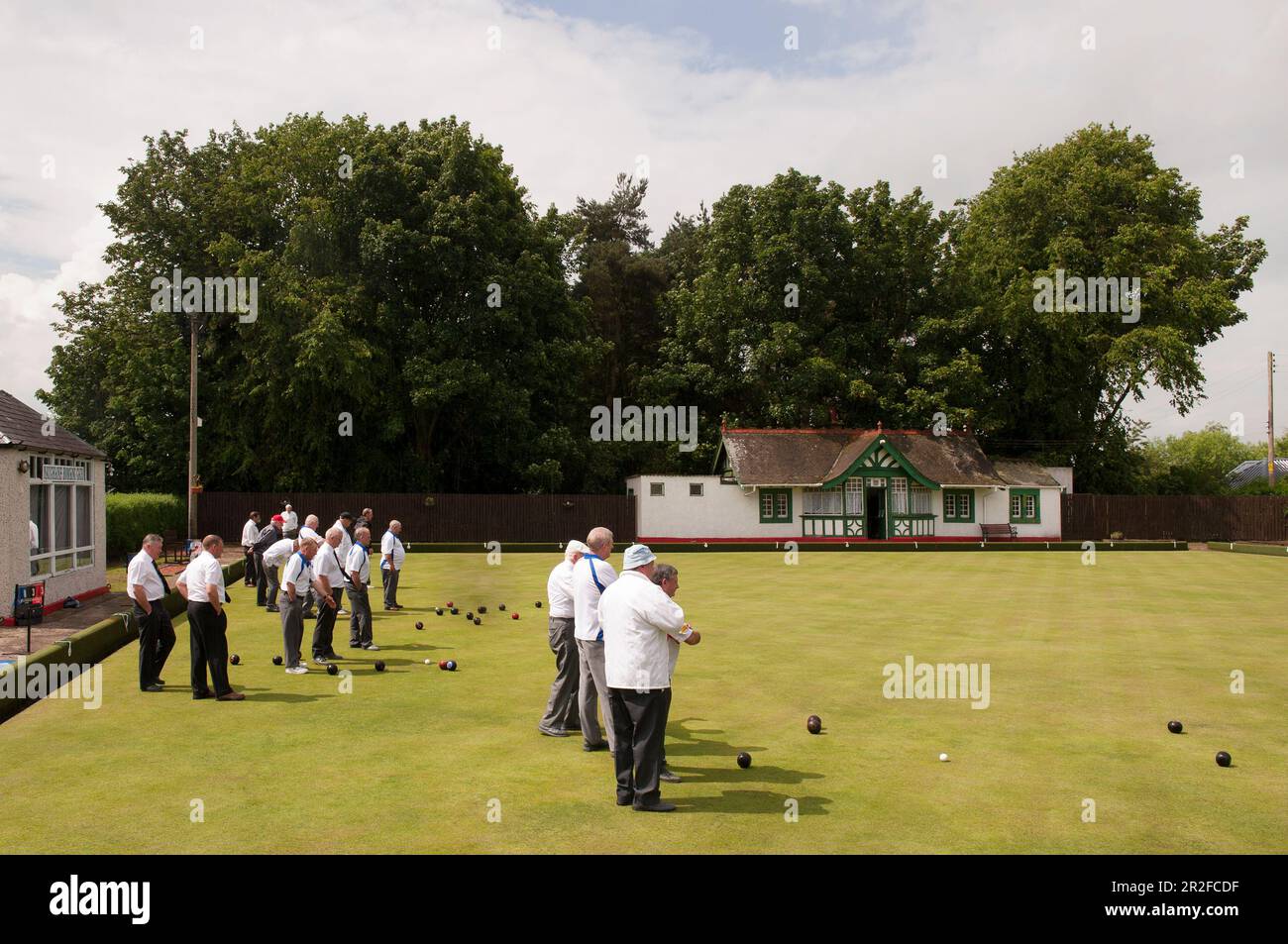 A large crowd of men play bowls in front of the pavilion at the Mauchline lawn bowling green in Mauchline; Ayrshire, Scotland, UK Stock Photo