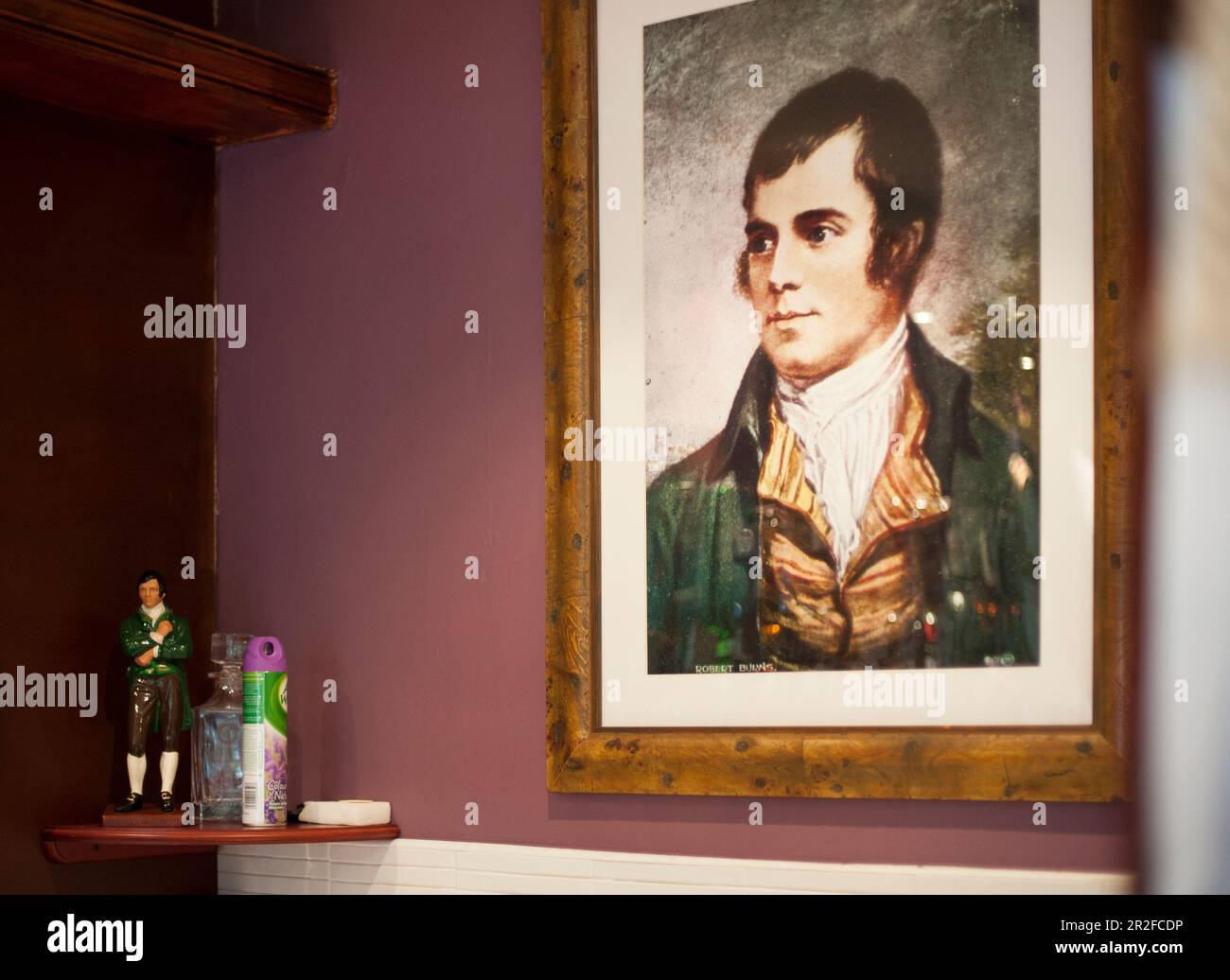 A framed portrait print of Robert Burns beside an ornament of Robert Burns and air freshner in the interior of the club house pavilion at the Mauchlin Stock Photo
