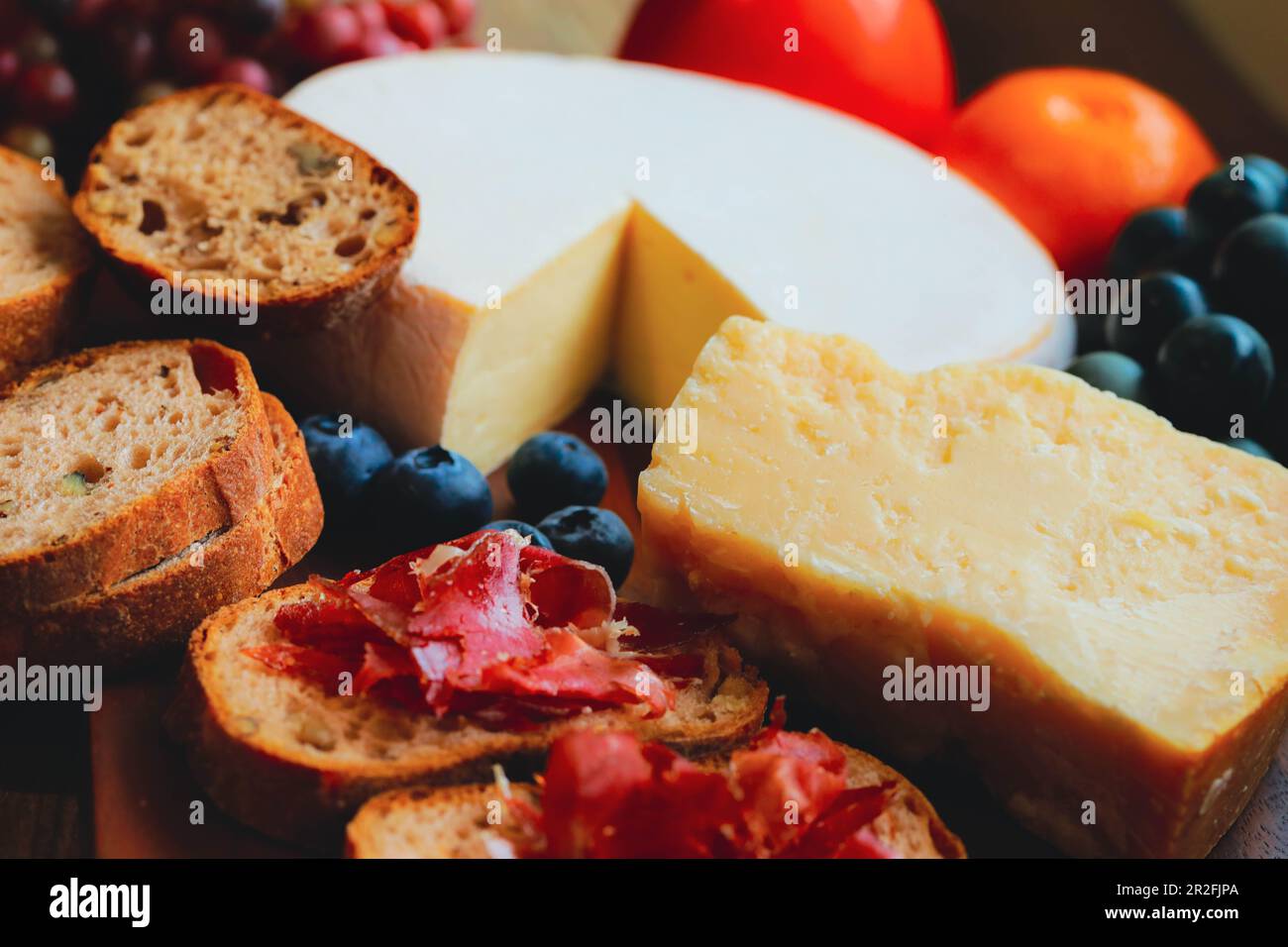Parmesan , reblochon cheese and ham jamon Bellota  on wooden board Stock Photo
