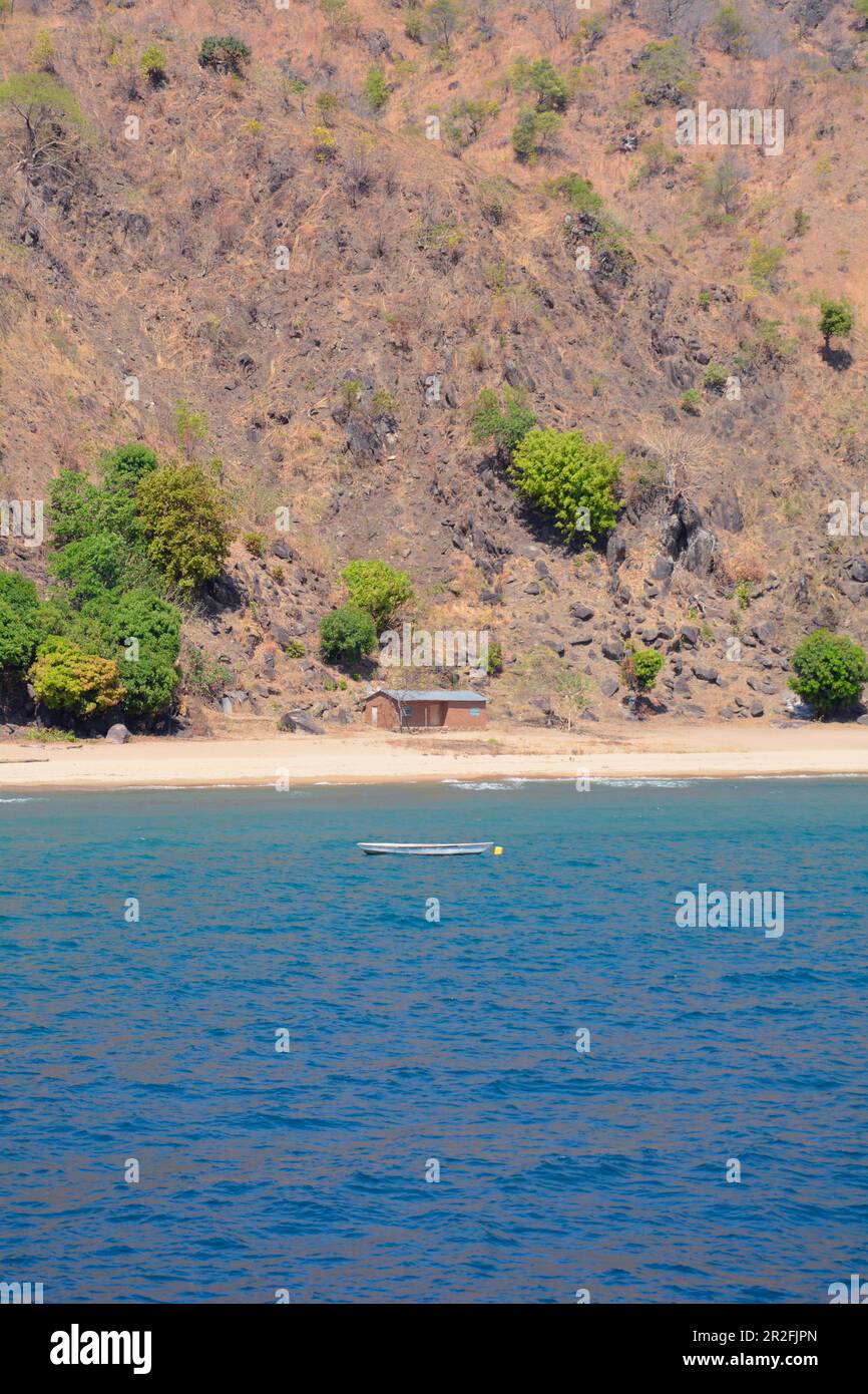 Malawi; Northern Region; Mountain landscape on the coast near Ruarwe; sparsely populated; lonely house on the beach; a fishing boat is anchored off th Stock Photo