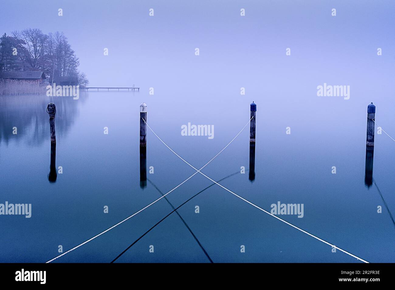 Ropes on wooden posts in the abandoned harbor in winter in Lake Starnberg, Seeseiten, Bavaria, Germany Stock Photo