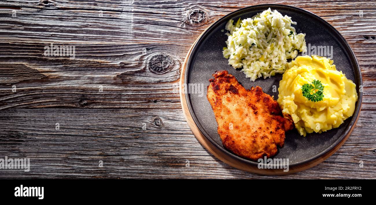 Chicken cutlet coated with breadcrumbs served with potatoes and cabbage Stock Photo