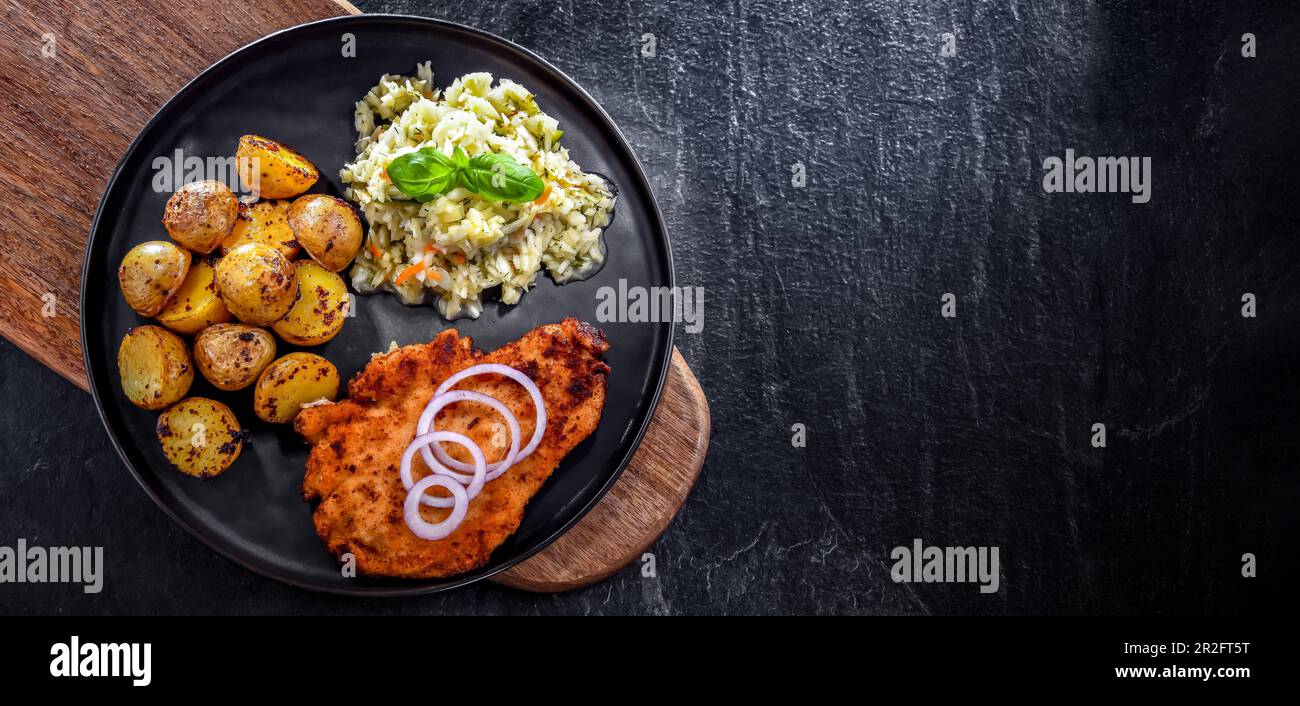 Chicken cutlet coated with breadcrumbs served with potatoes and cabbage Stock Photo