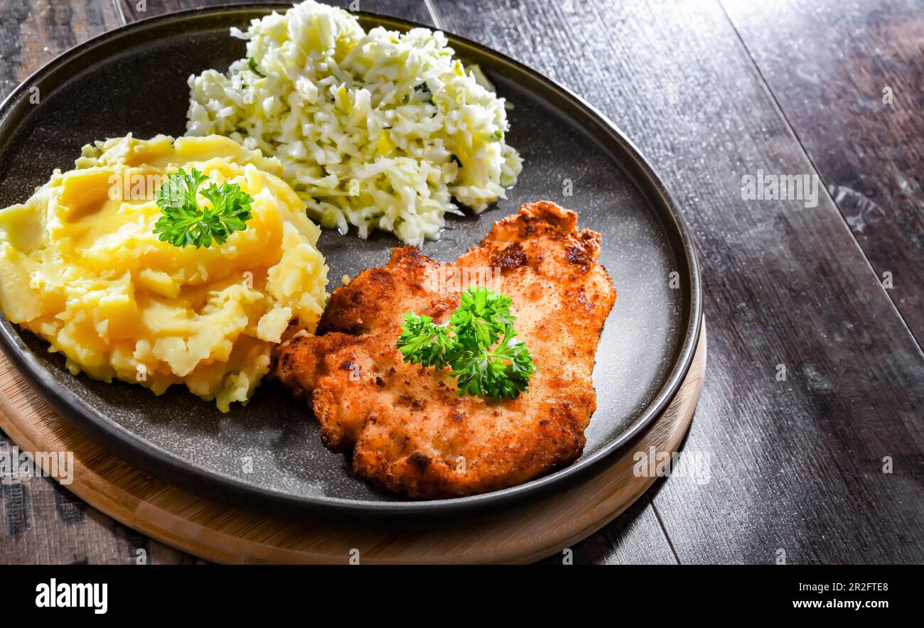 Chicken cutlet coated with breadcrumbs served with potatoes and cabbage Stock Photo