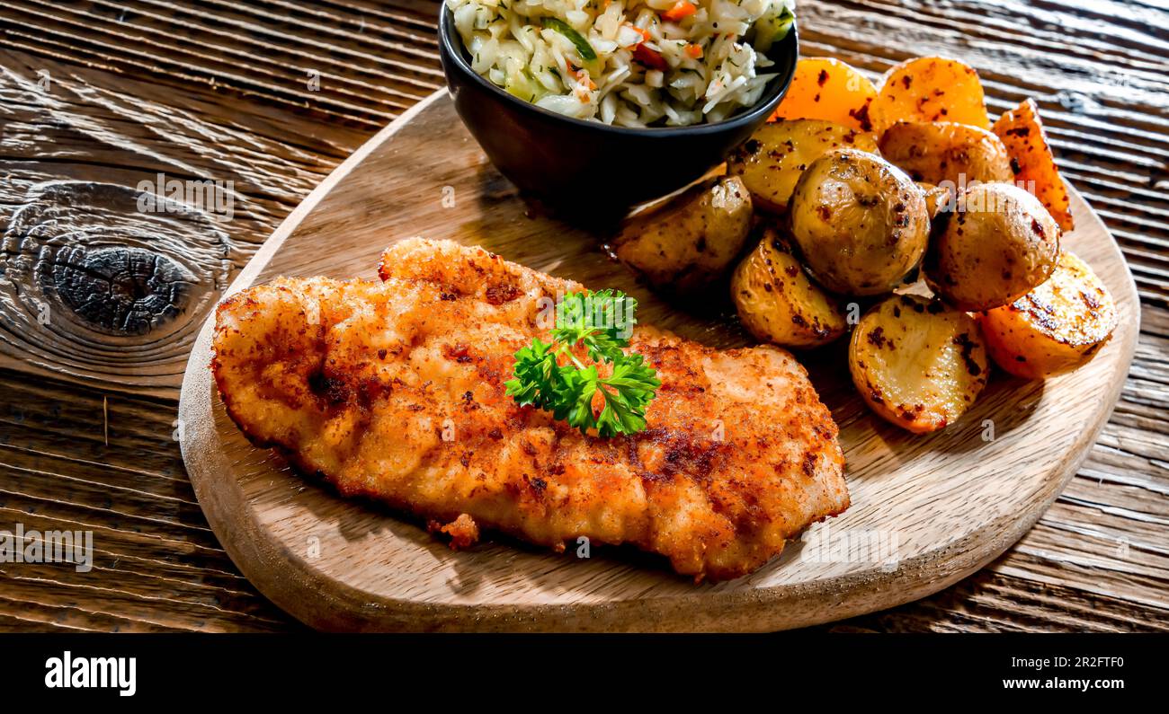 Chicken cutlet coated with breadcrumbs served with potatoes and cabbage Stock Photo