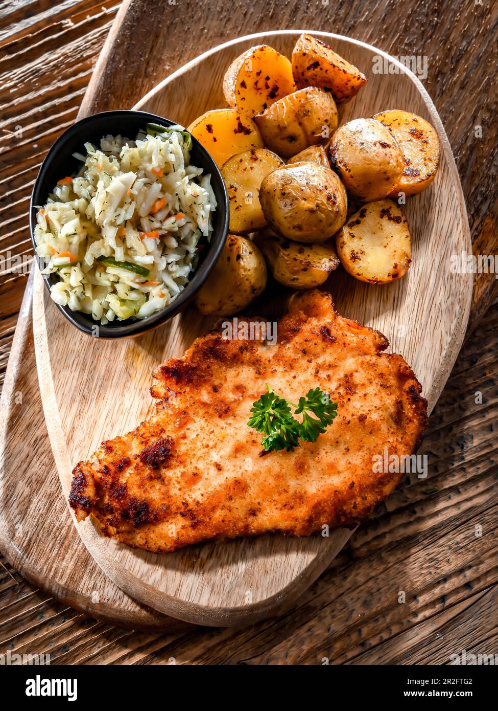 Chicken cutlet coated with breadcrumbs served with potatoes and cabbage Stock Photo