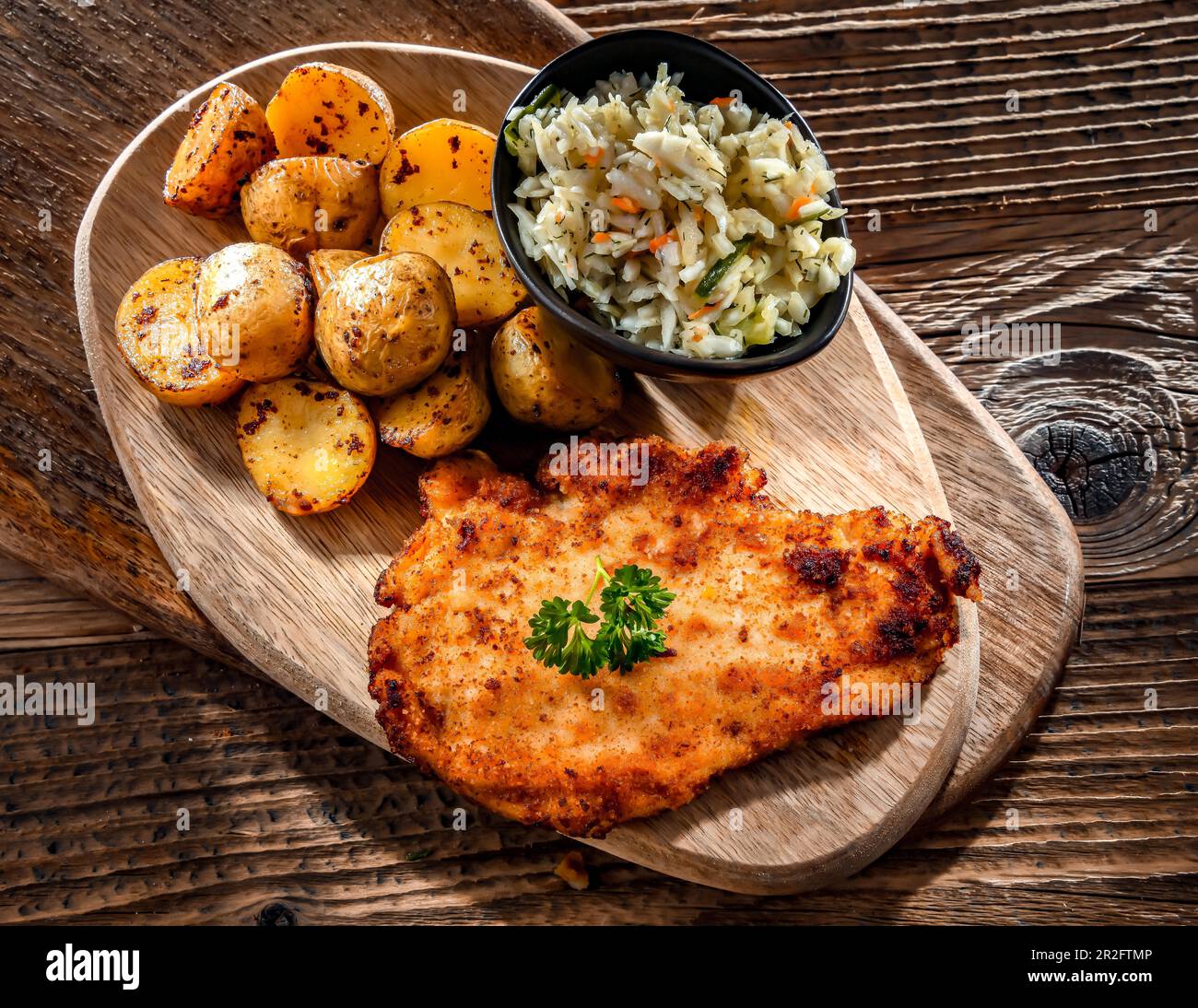 Chicken cutlet coated with breadcrumbs served with potatoes and cabbage Stock Photo