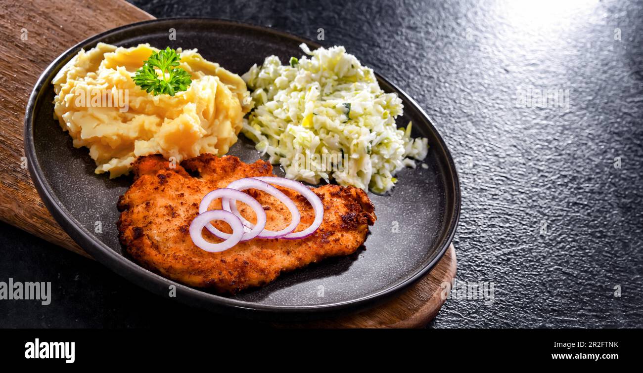 Chicken cutlet coated with breadcrumbs served with potatoes and cabbage Stock Photo