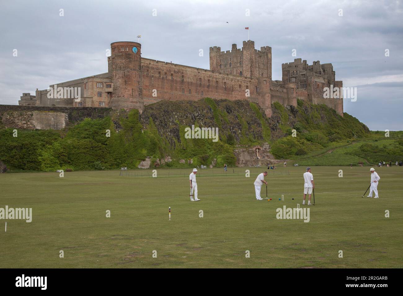 Croquet player dressed in white in front of Bamburgh Castle, England