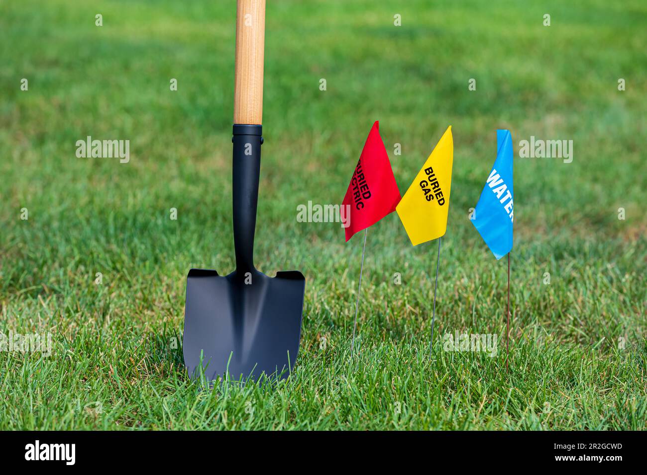 Buried electric, natural gas and water utility warning flag with shovel. Notify utility locate company for underground utilities, call before you dig Stock Photo