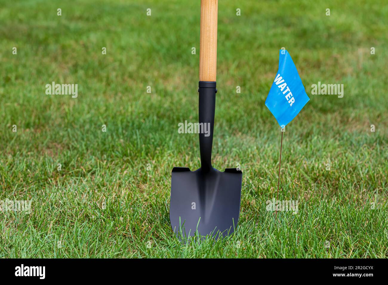 Water utility warning flag with shovel. Notify utility locate company for underground utilities, call before you dig and digging safety concept Stock Photo