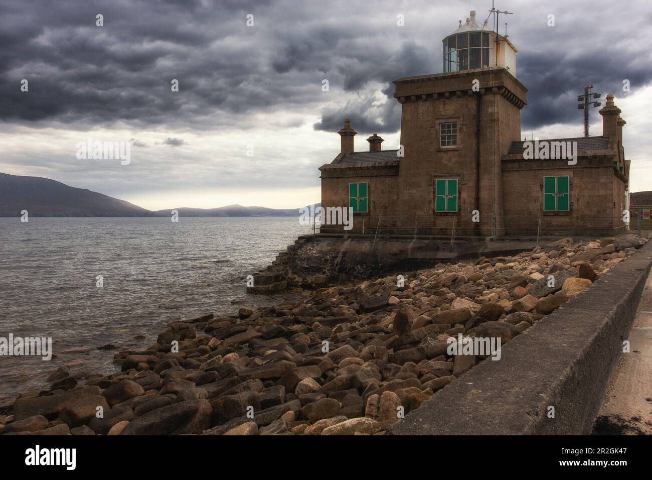 Blacksod lighthouse against dark rain clouds. quay wall. Fallmore ...