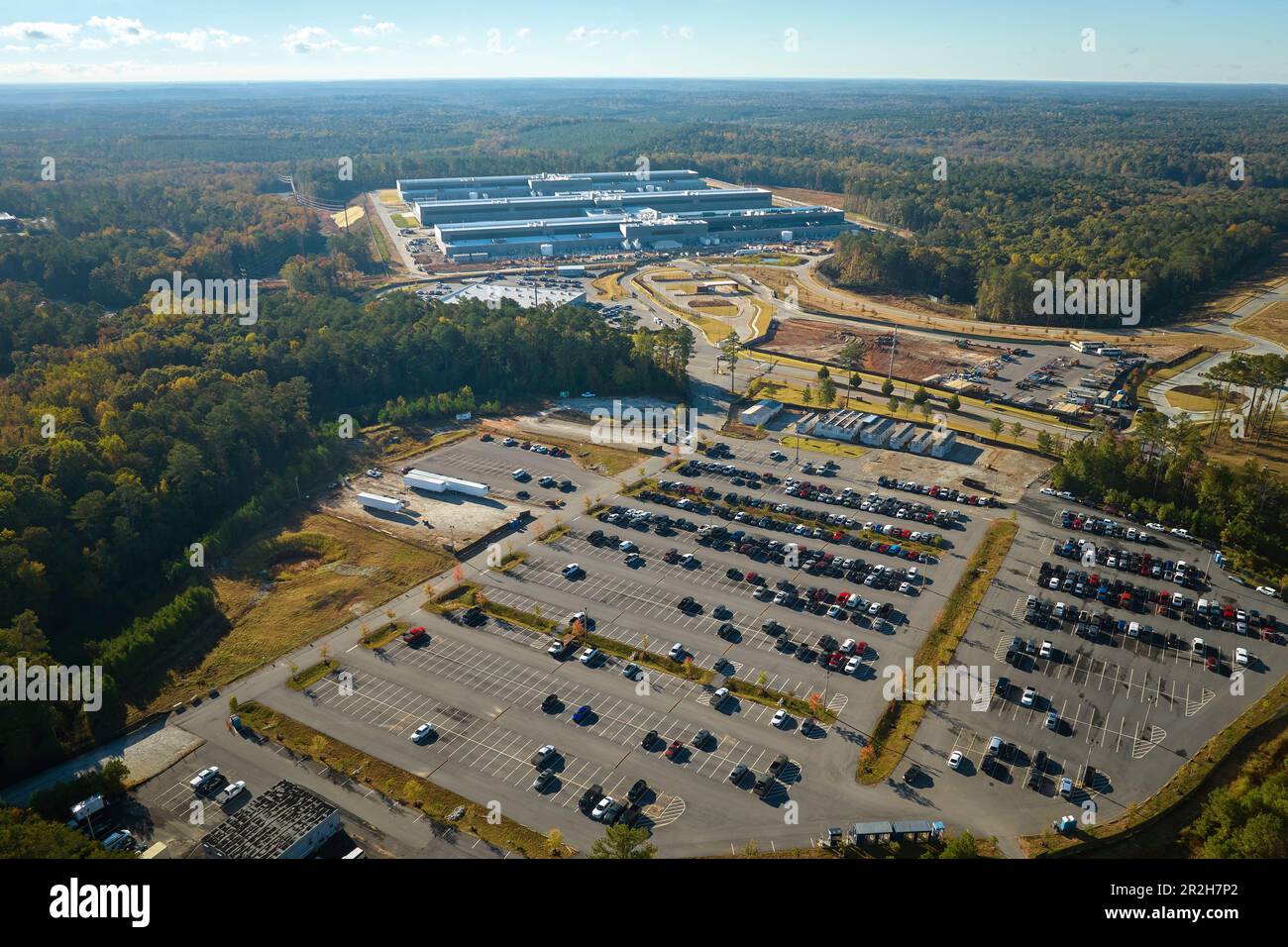 Many associate cars parked on big parking lot in front of industrial