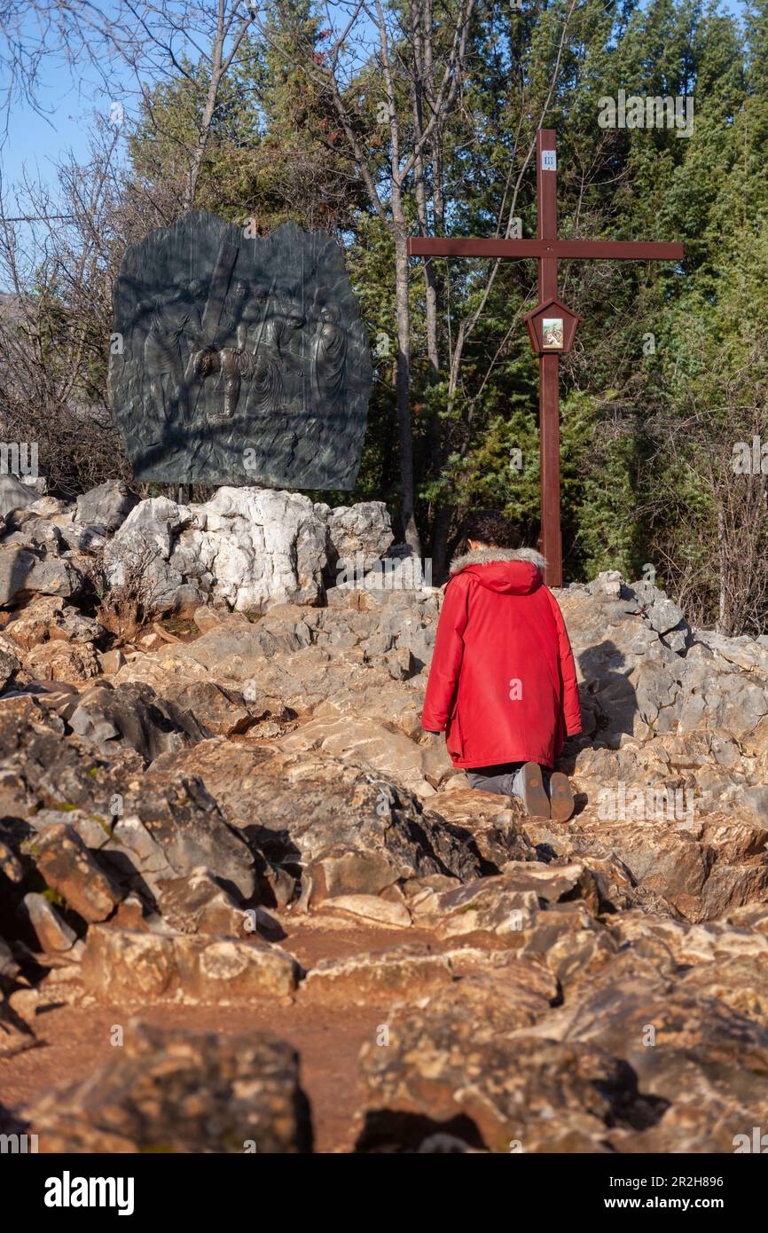 A woman kneeling in prayer at the 2nd station of the Way of the Cross on Mount Križevac in Medjugorje. Stock Photo
