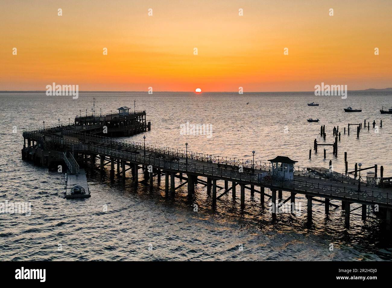 The sky glows orange during the sunrise above the pier at Swanage in Dorset. Stock Photo