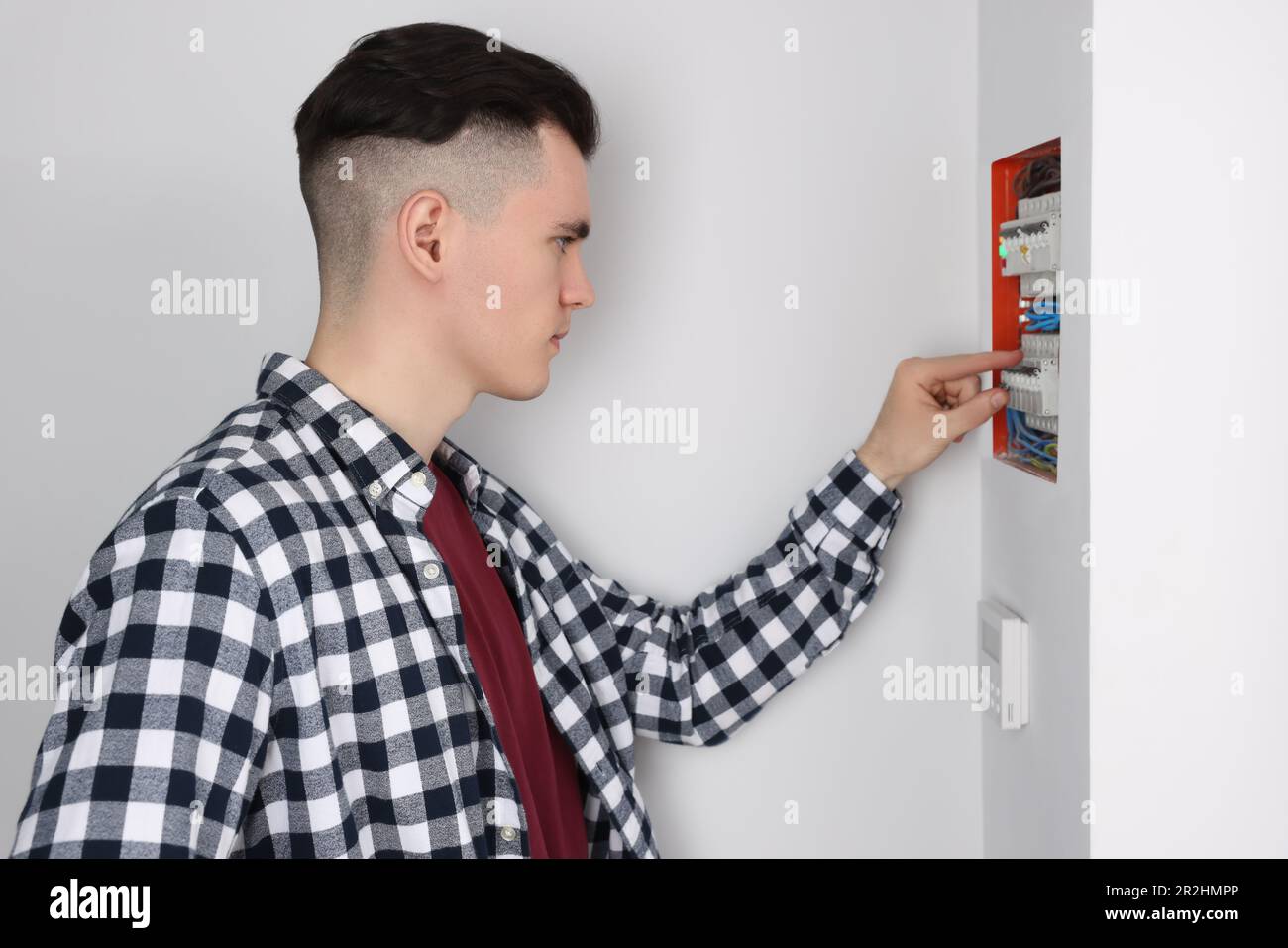 Young handyman pressing switch on electrical panel board indoors Stock ...