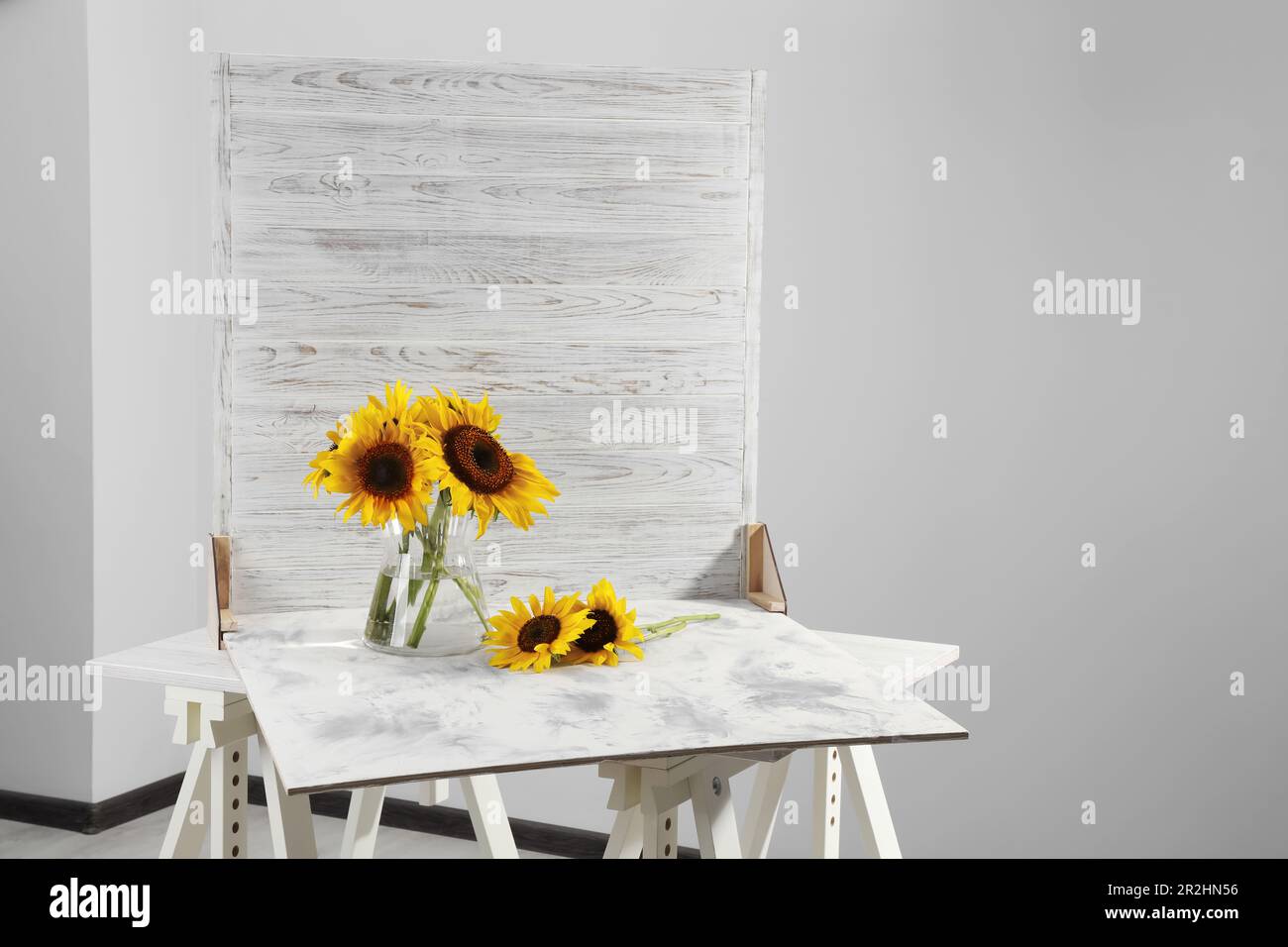 Glass vase with beautiful sunflowers and double-sided backdrop on table ...