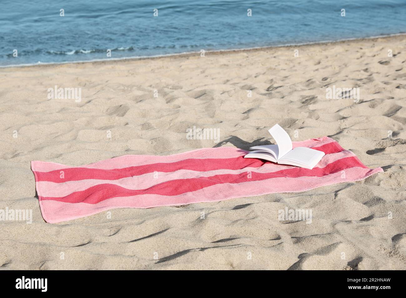 Beach towel and open book on sand near sea Stock Photo - Alamy